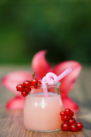 jar of cold pink cocktail with straw on green background bokehの写真素材