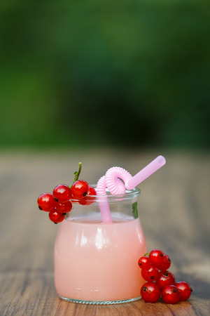 jar of cold pink cocktail with straw on green background bokehの写真素材