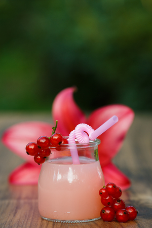 jar of cold pink cocktail with straw on green background bokehの写真素材