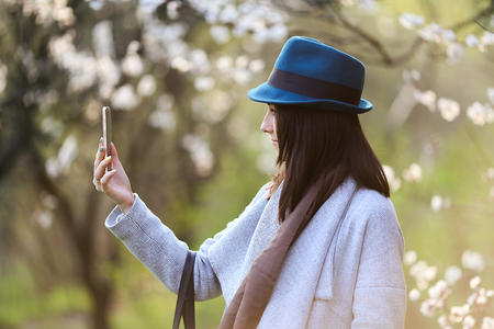 Beautiful girl posing in a blooming garden with phoneの写真素材