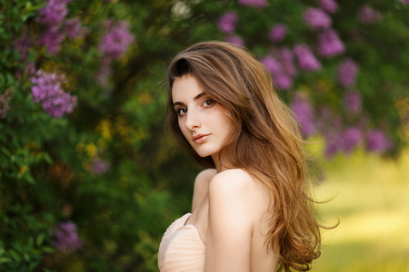 Romantic portrait of young beautiful girl standing at summer park and looking forward.の写真素材