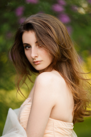 Romantic portrait of young beautiful girl standing at summer park and looking forward.の写真素材