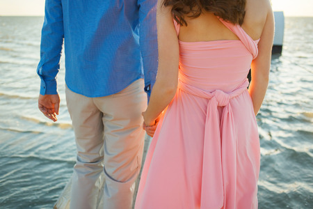 Close up of loving couple holding hands on a beach near the sea
