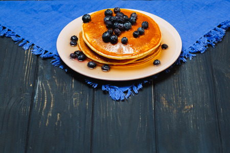 Pancakes with honey and blueberries on a blue napkinの写真素材