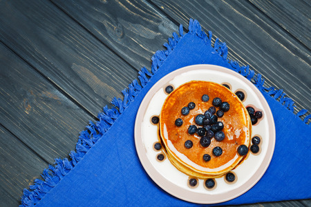 Pancakes with honey and blueberries on a blue napkinの写真素材