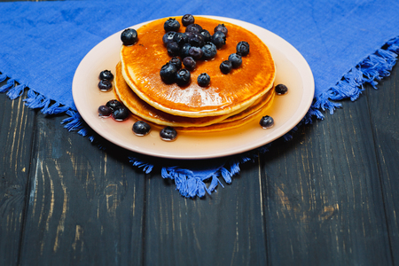 Pancakes with honey and blueberries on a blue napkinの写真素材