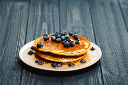 Pancakes with honey and blueberries on wooden tableの写真素材