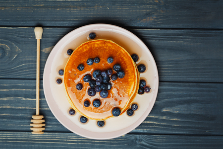 Tasty pancakes with blueberries and honey on tableの写真素材