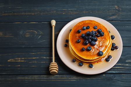 Tasty pancakes with blueberries and honey on tableの写真素材