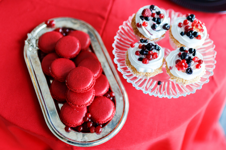 Rasperry macaroons , currant berries on a tray on red tableの写真素材