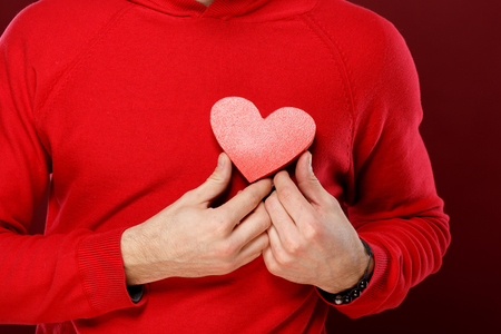 Young man with a red heart in his hands on Valentine dayの写真素材