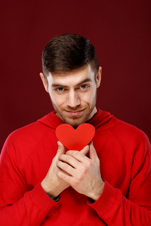 Young handsome man with a red heart in his hands on Valentine dayの写真素材