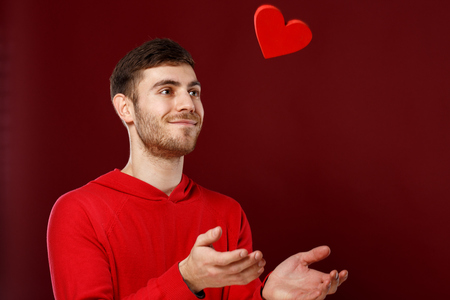 Young handsome man with a red heart in his hands on Valentine dayの写真素材