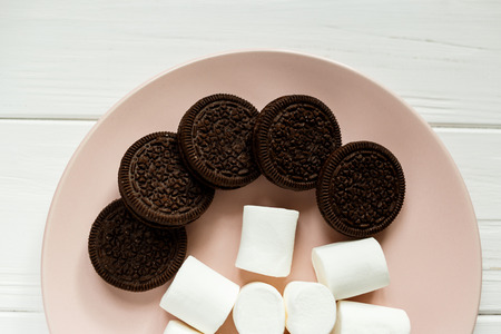 chocolate Cookies and marshmallows on a pink plate on a wooden tableの写真素材