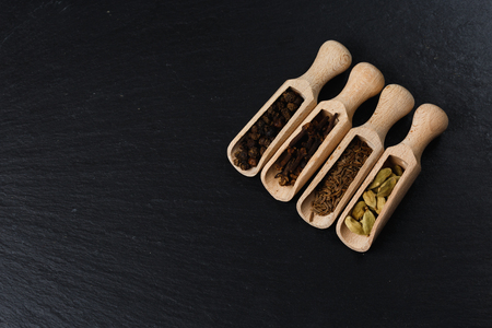 Various of spices and herbs in wooden spoons. Flat lay of spices on black stoneの写真素材