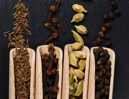 Various of spices and herbs in wooden spoons. Flat lay of spices on black stoneの写真素材