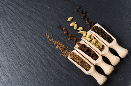 Various of spices and herbs in wooden spoons. Flat lay of spices on black stoneの写真素材
