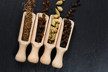 Various of spices and herbs in wooden spoons. Flat lay of spices on black stoneの写真素材