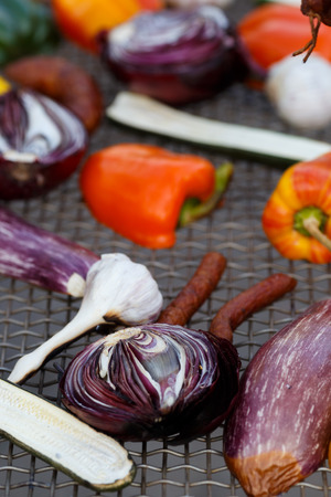 Grilled vegetables on a baking sheet, orange pepper and yellow pepper, zucchini, eggplant, hunting sausages, onion and garlic. Street food.の写真素材