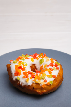 donut in sugar glaze with candied fruits on a blue plateの写真素材