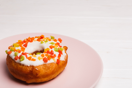 donut in sugar glaze with candied fruits on a pink plateの写真素材