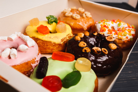 Six colorful round donuts with sprinkles in the box. Flat lay, top view.
