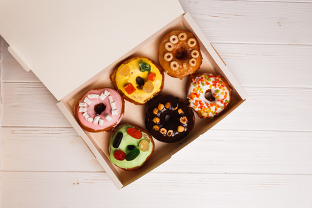 Six colorful round donuts with sprinkles in the box. Flat lay, top view.の写真素材