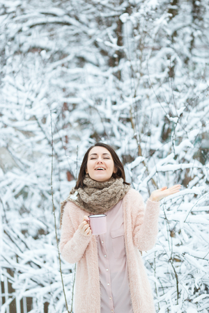 sweet girl with a pink cup of coffee in the winter forestの写真素材