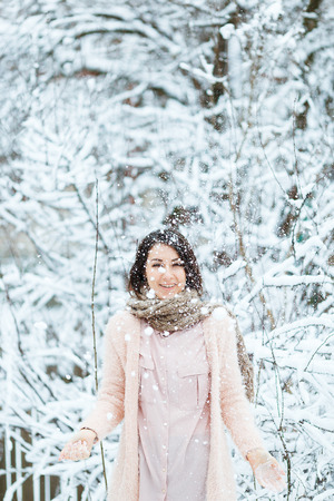 cute girl plays with falling snow in the winter forestの写真素材