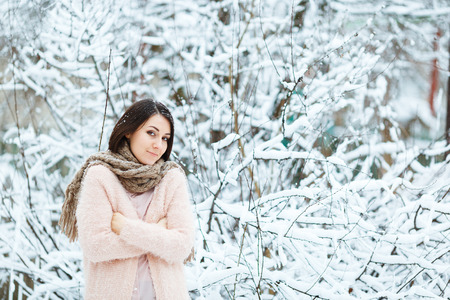 cute girl plays with falling snow in the winter forestの写真素材
