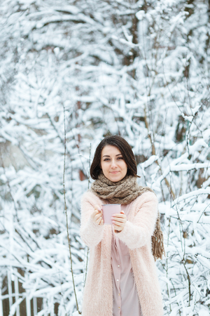 cute girl with a pink cup of coffee in the winter forestの写真素材