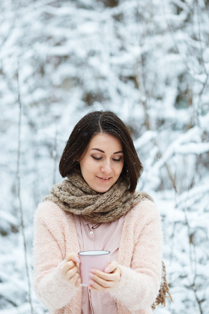 cute girl with a pink cup of coffee in the winter forestの写真素材