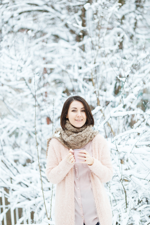 cute girl with a pink cup of coffee in the winter forestの写真素材