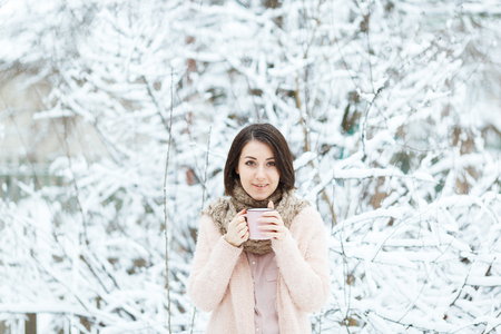 cute girl with a pink cup of coffee in the winter forestの写真素材