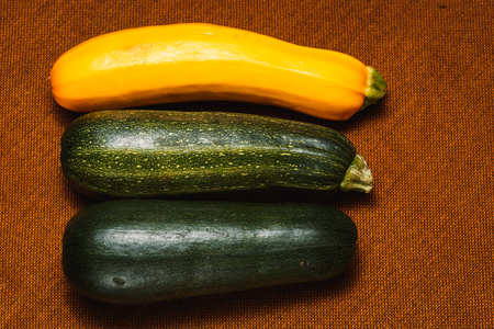 Fresh yellow and green zucchini on brown backgroundの写真素材