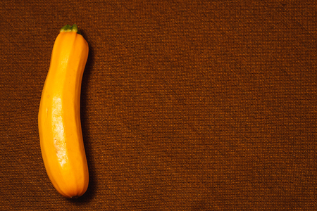 Raw yellow vegetable marrow on brown textile background. Healthy raw food, top view, flat lay.の写真素材