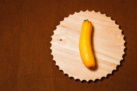 Raw yellow vegetable marrow on brown textile background. Healthy raw food, top view, flat lay.の写真素材