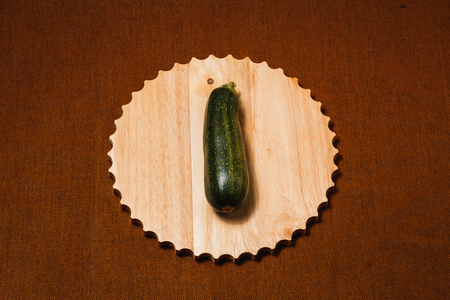 Raw green vegetable marrow on brown textile background. Healthy raw food, top view, flat lay.の写真素材