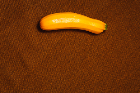 Raw yellow vegetable marrow on brown textile background. Healthy raw food, top view, flat lay.の写真素材