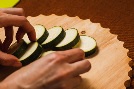 Green zucchini sliced with knife on wooden cutting boardの写真素材