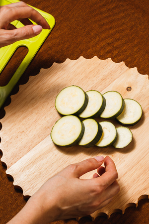 Green zucchini sliced with knife on wooden cutting boardの写真素材