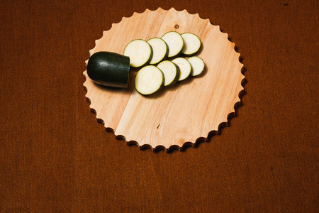 Green zucchini sliced with knife on wooden cutting boardの写真素材
