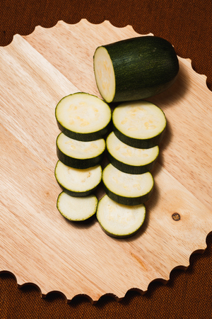 Green zucchini sliced with knife on wooden cutting boardの写真素材