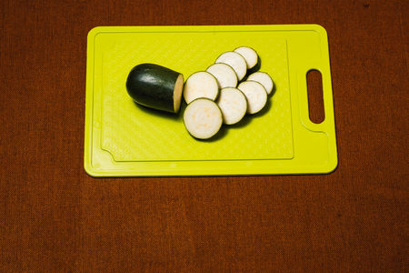 Green zucchini sliced with knife on plastic cutting boardの写真素材