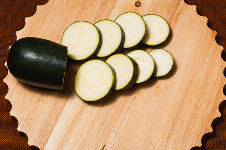 Green zucchini sliced with knife on wooden cutting boardの写真素材