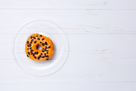 Orange donut in sugar glaze on a transparent plateの写真素材