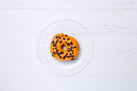 Orange donut in sugar glaze on a transparent plateの写真素材