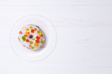 donut in sugar glaze with candied fruit on a transparent plateの写真素材
