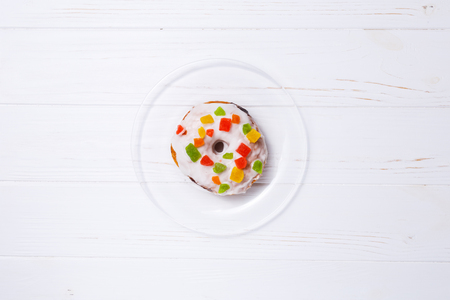 donut in sugar glaze with candied fruit on a transparent plateの写真素材