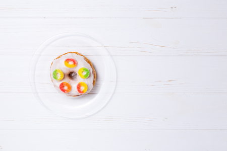 donut in sugar glaze with candied fruit on a transparent plateの写真素材